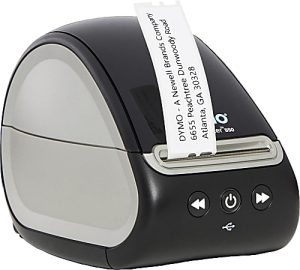 Compact label printer with a printed label showing company details. Black and gray design with control buttons.