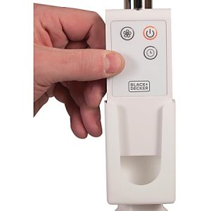 Hand pressing a button on a Black+Decker fan remote with power, speed, and timer controls.