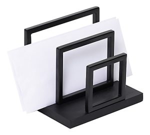 Black metal letter holder with geometric design holding several white envelopes on a white background.