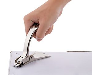 Hand using a chrome staple remover on a white document, close-up.